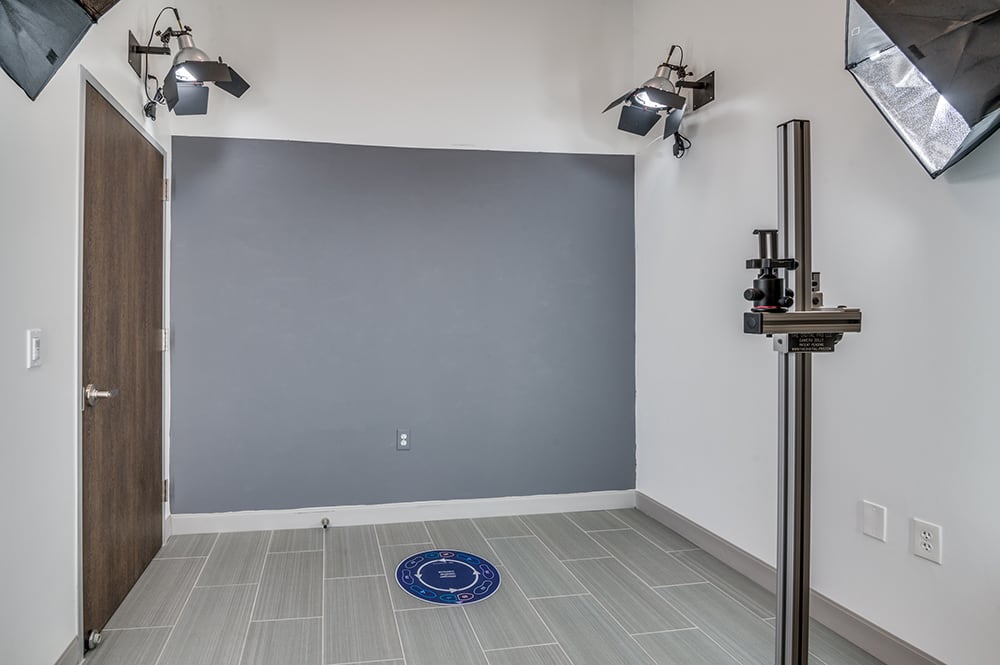 Professional medical photography suite with a grey background wall, floor alignment marker, and studio lighting setup.
