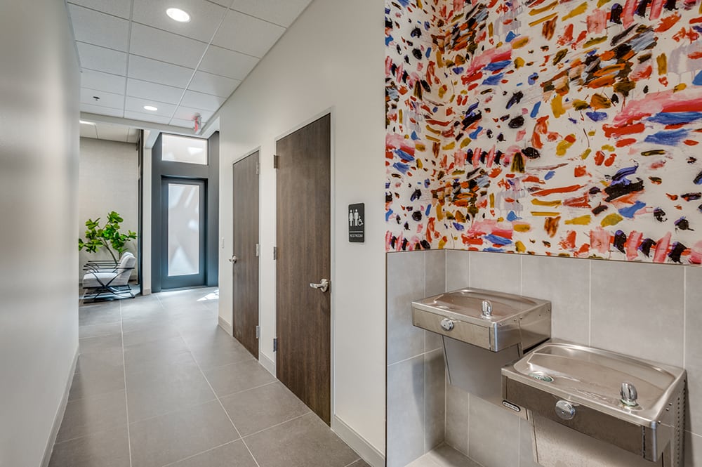 Medical clinic hallway featuring double drinking fountains set against a vibrant, multi-colored abstract accent wall.